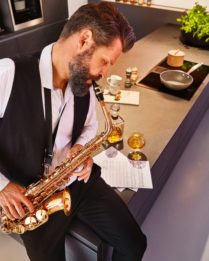 Musiker spielt Saxophon auf Kücheninsel