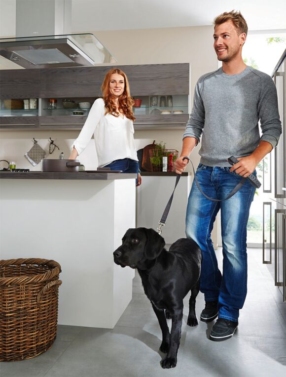 Mann und Frau mit Hund in Küche, Mann hält Hund an Leine