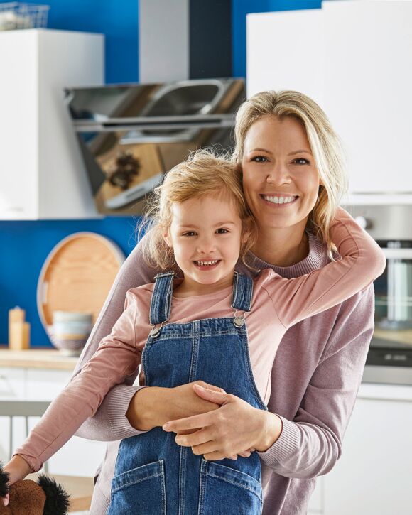 Mutter umarmt Tochter in Küche