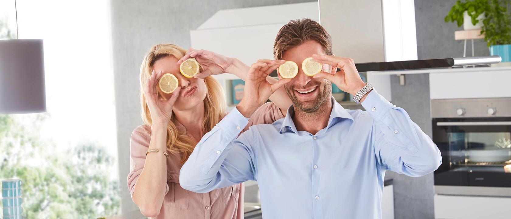 Mann und Frau lachen und halten Zitronen vor Augen
